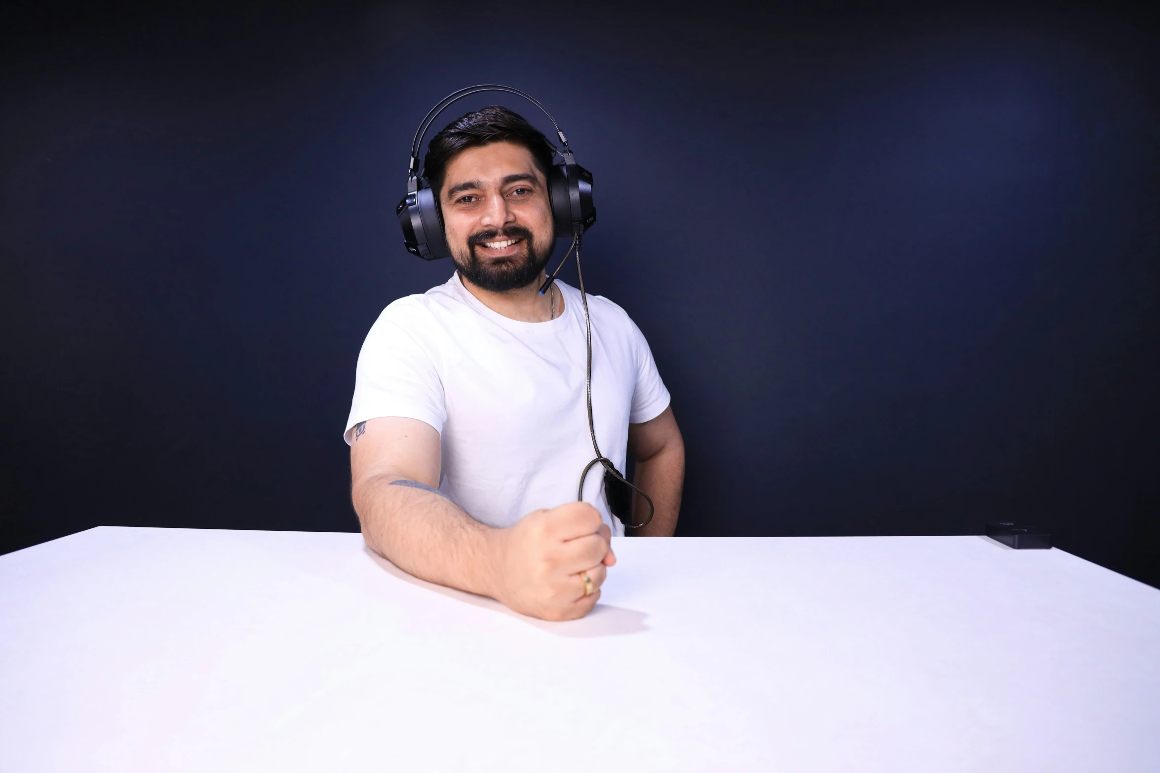 a guy wearing headphones sitting behind a table