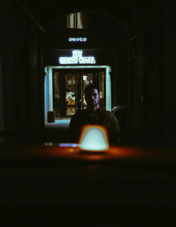 a man stands in front of a bar while the night comes on