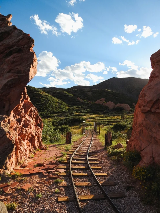 a narrow train track with rocks and grass