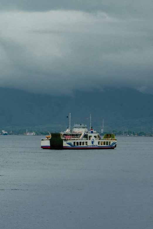 a large ferry on a lake with clouds in the sky