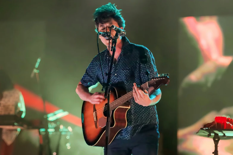 a man holding an acoustic guitar while performing