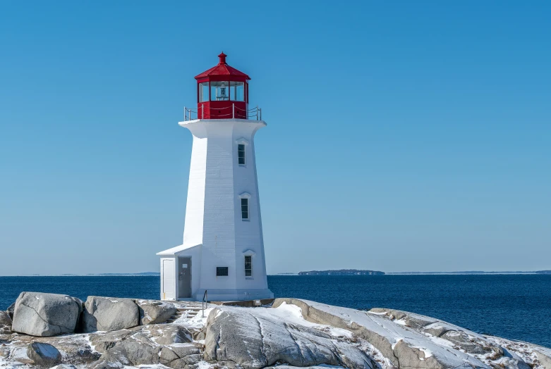 a tall lighthouse sits on top of a rocky beach