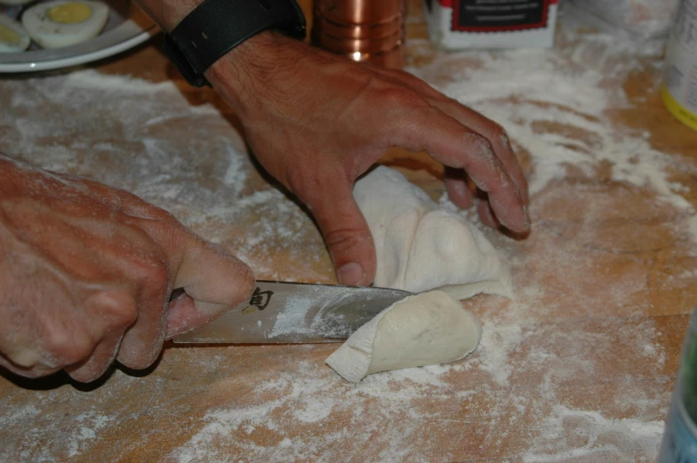 a person holding a knife and  a pizza dough