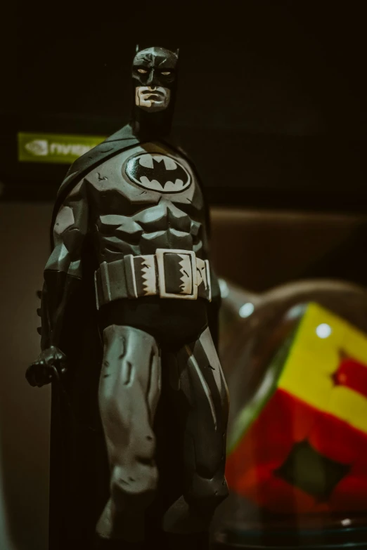 a toy batman standing next to a large flag