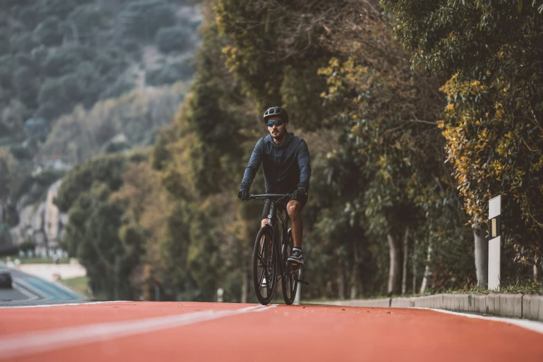 man riding bicycle on road surrounded by trees