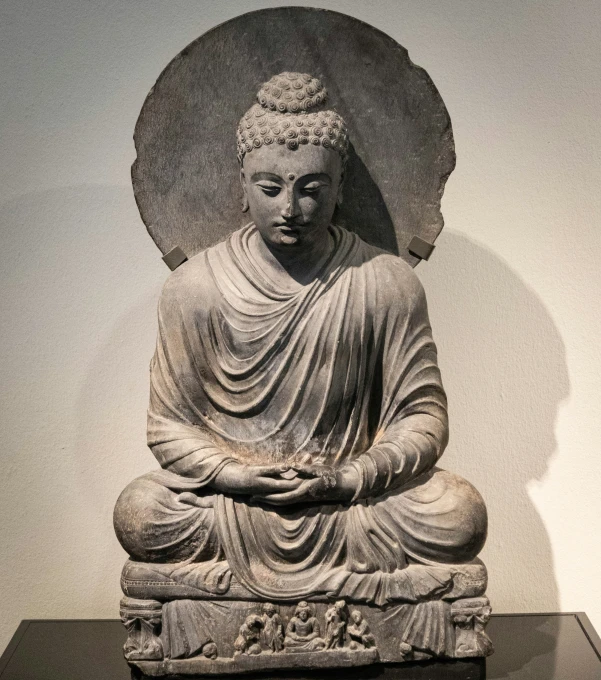 an old buddha statue with a large circular object next to it