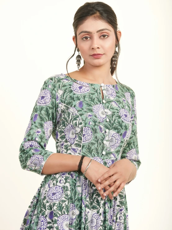 woman with curly hair, in a green dress with blue flowers on it