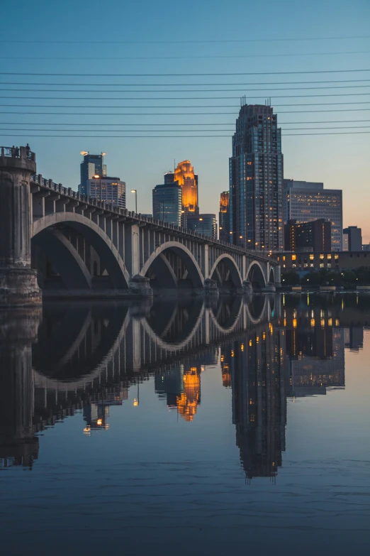 an image of a bridge at dusk with buildings reflecting in it