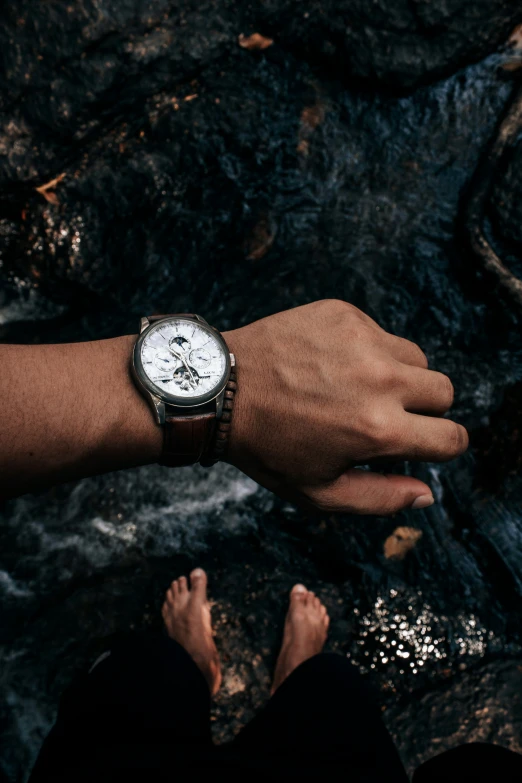 a person wearing a watch sitting on a stone surface