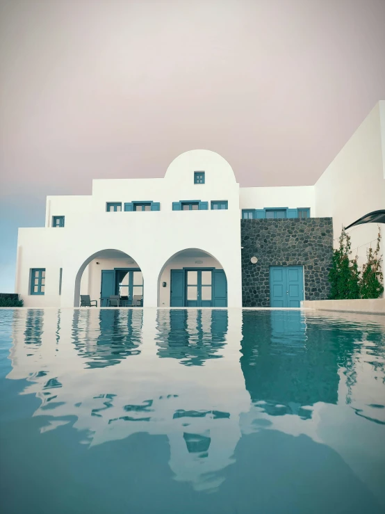 a white and gray building is reflected in the water