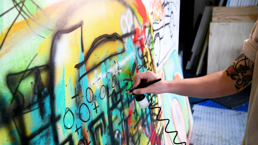 a person with a tattoo painting a colorful wall