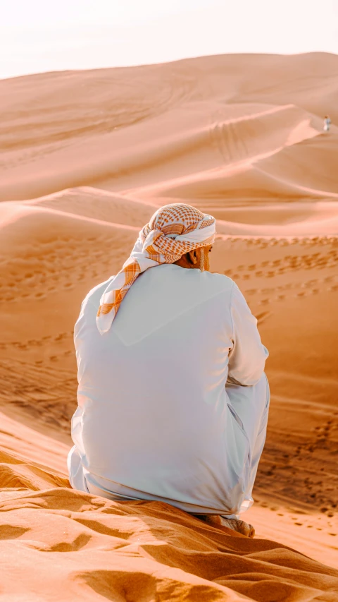 a person sitting on the sand in the desert