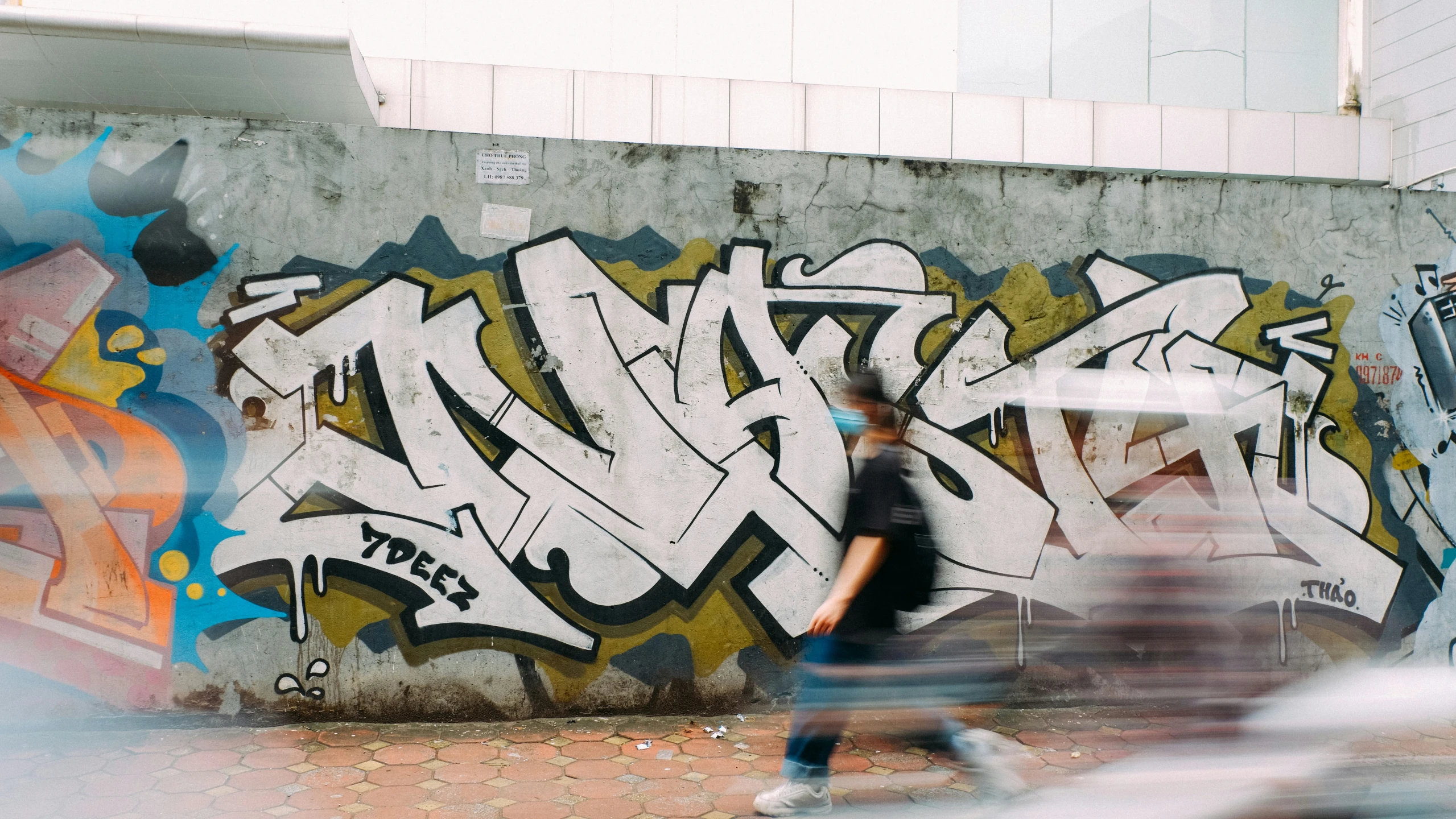 a boy walking past a graffiti covered wall