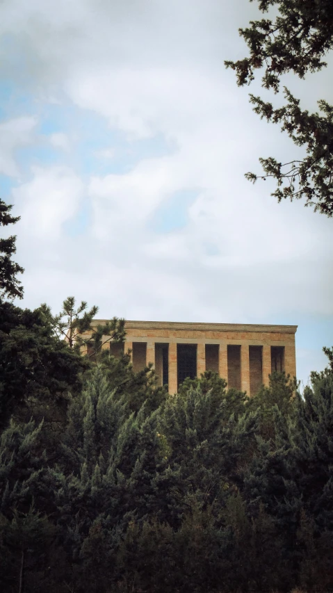 a tall stone structure near many trees and clouds