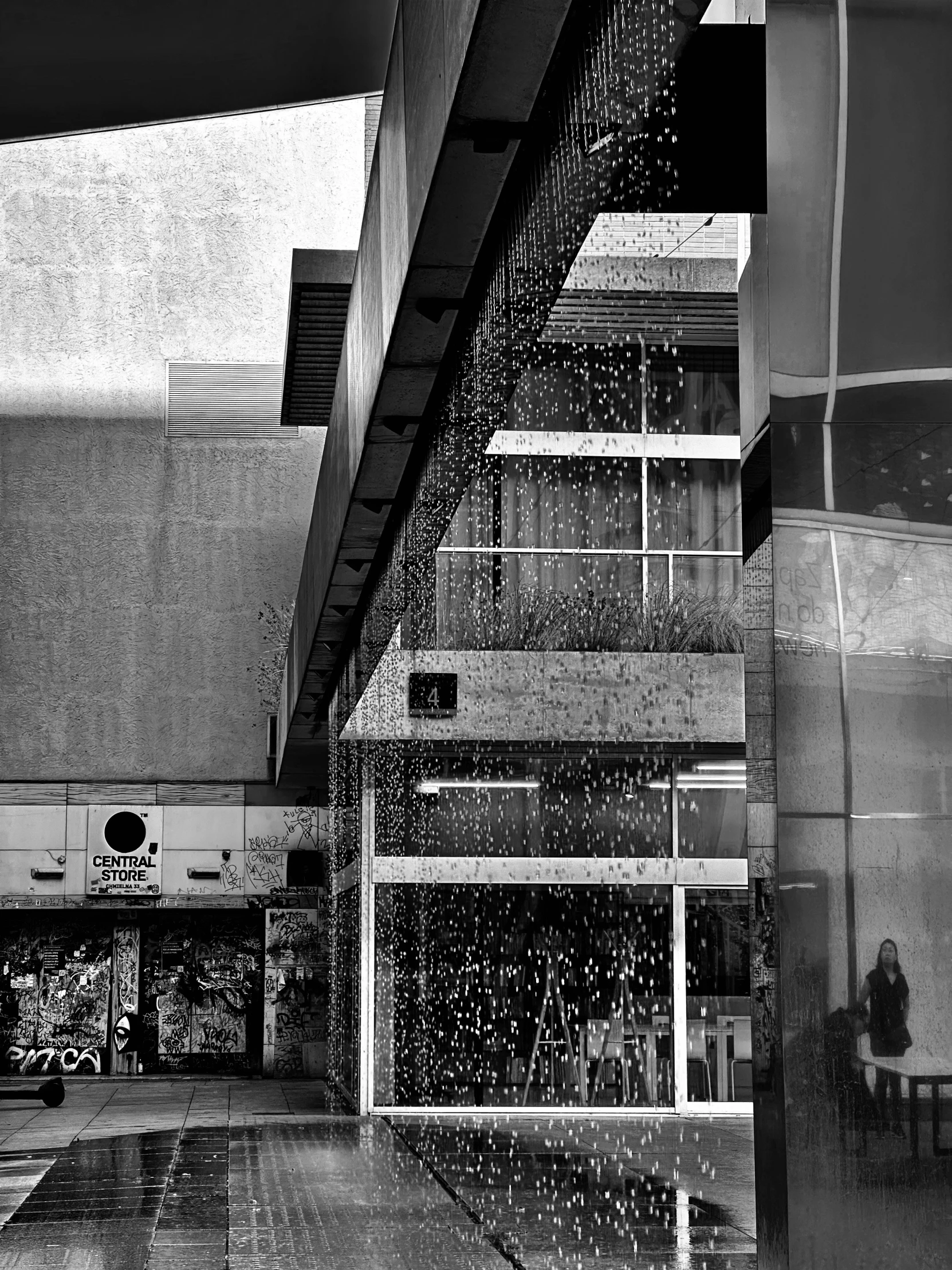 water falling from the roof of a building with an overhead handrail