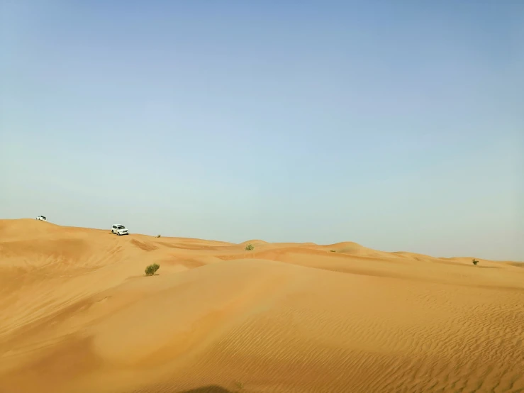 two people with an airplane are flying in the sky above the dunes