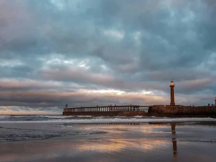 a lighthouse sits next to the ocean and a pier