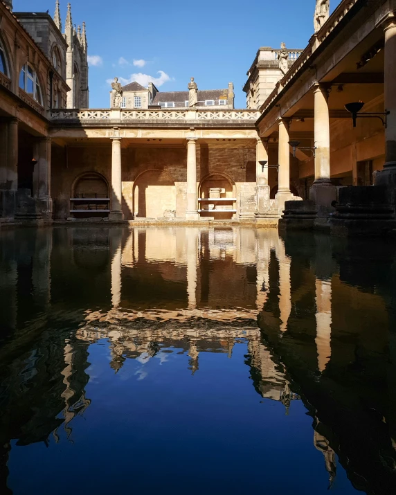 a still pond surrounded by old stone buildings