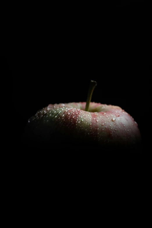 a wet green apple sitting on top of a black background
