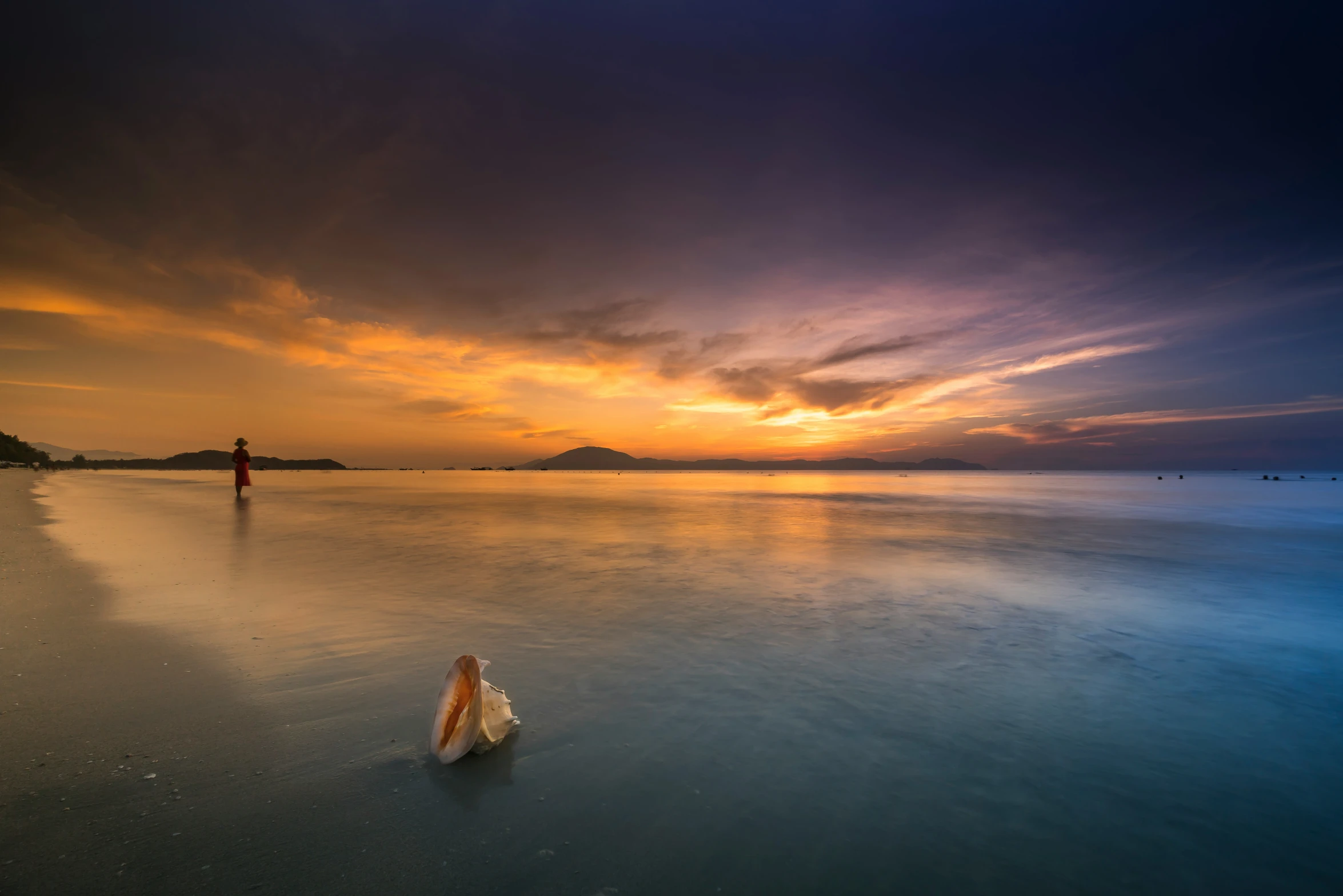 a person on a beach during sunset with the sun going down