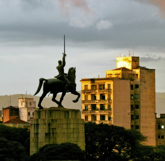 a statue of an old soldier riding a horse near a city skyline