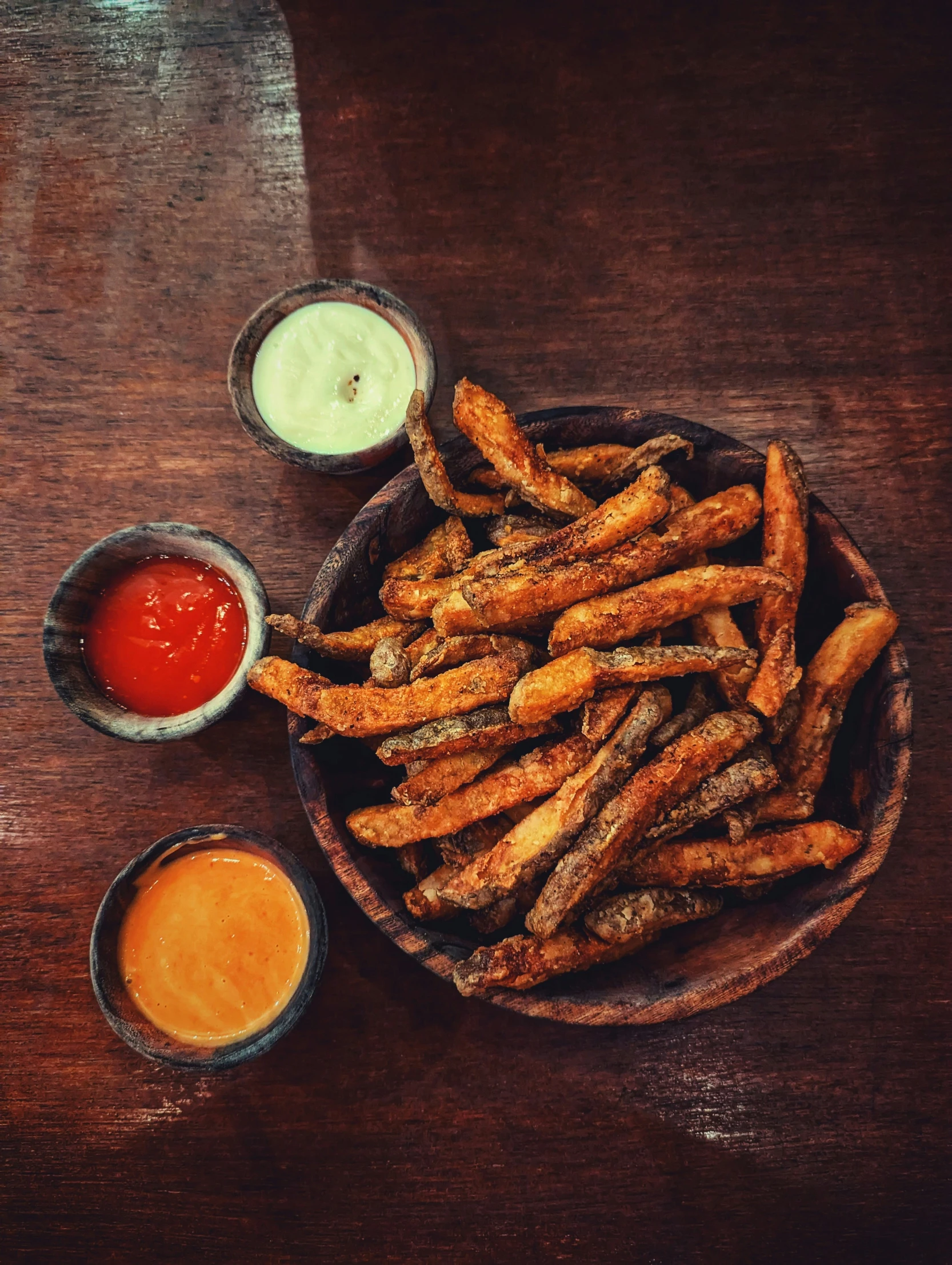 a wooden bowl filled with french fries and sauce