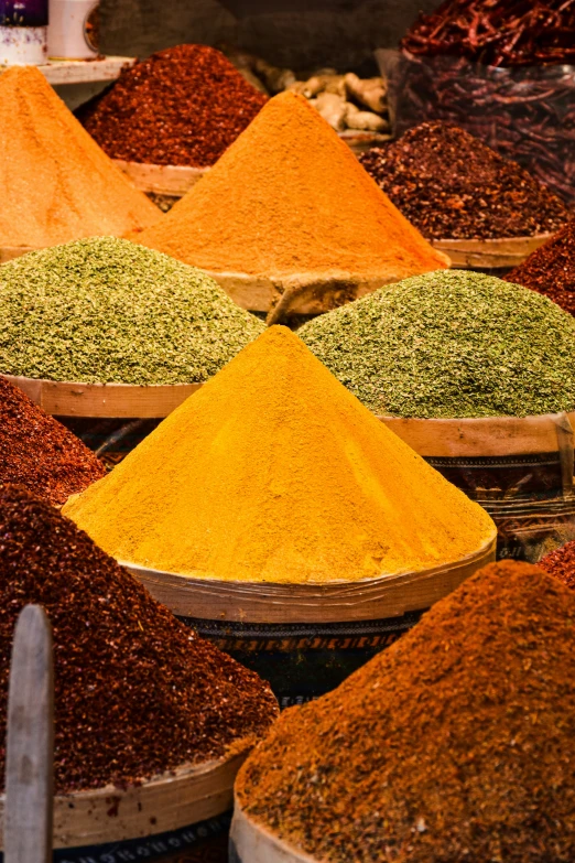 different colors of spices in baskets at a market