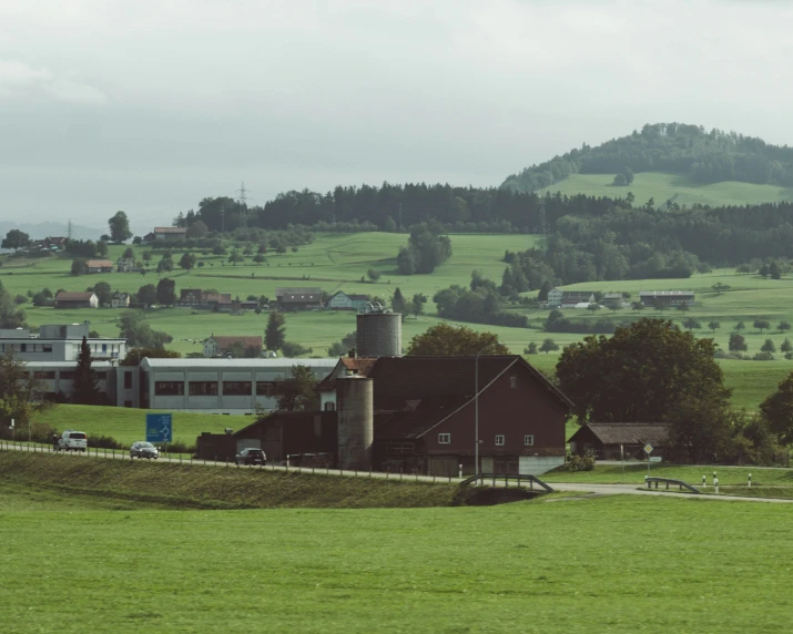 a farm with a silo and cars parked in the front