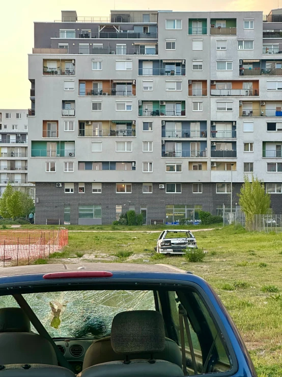 a blue car with its hood open in front of a grassy field