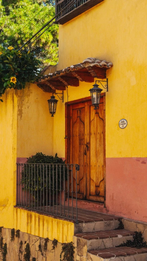 the building is painted yellow and features an iron balcony