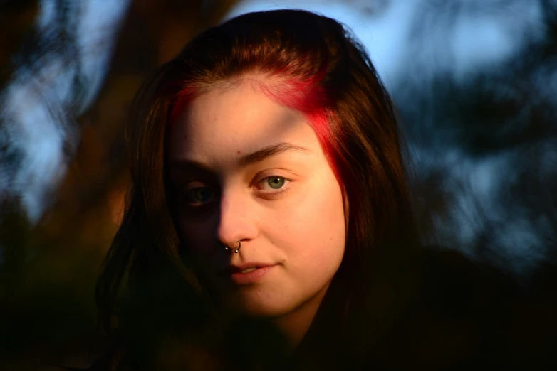 a girl with piercings is shown in a dark portrait