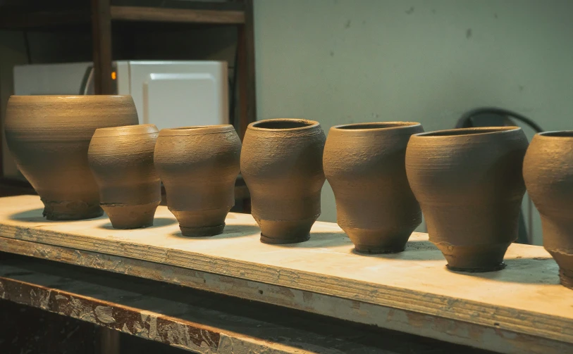 a row of ceramic pots sitting on top of a wooden shelf