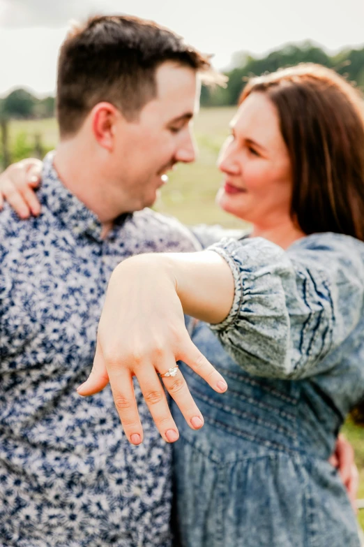 a couple pointing out their hand in the middle of an open field