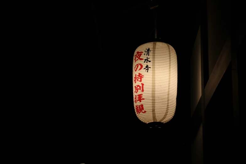a white hanging lantern lit with chinese writing