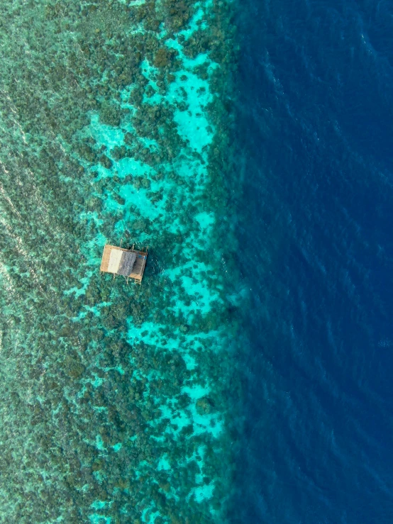 a view from above showing the crystal blue water and a small wooden cabin near a shoreline