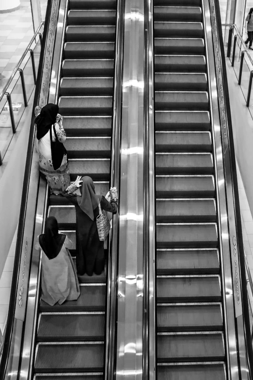 two people sitting on an escalator in a building