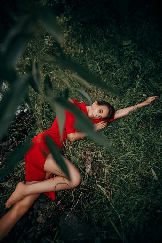 a woman in red is laying on the grass