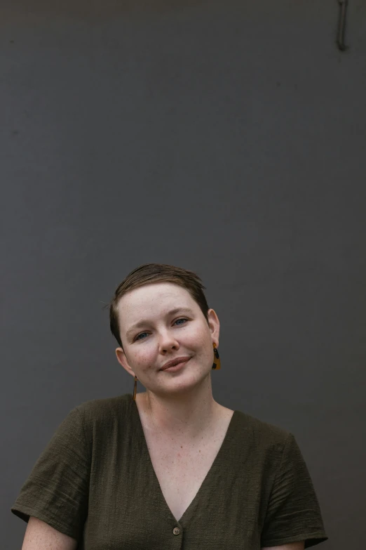 a woman smiling and wearing a necklace with gold colored beads