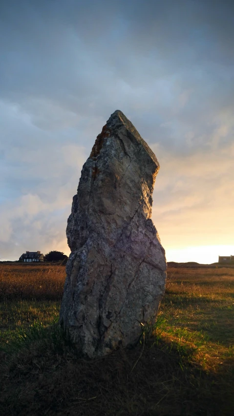 a rock sitting in the middle of a field