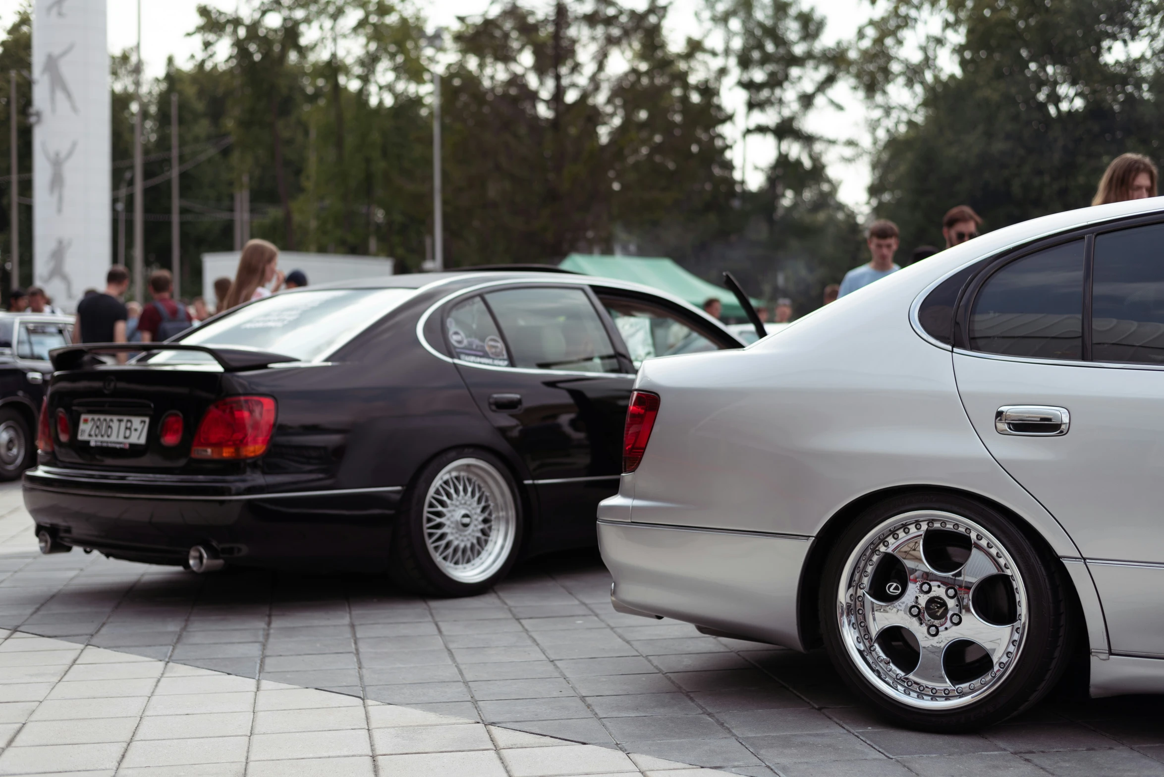 two cars in parking lot with people around