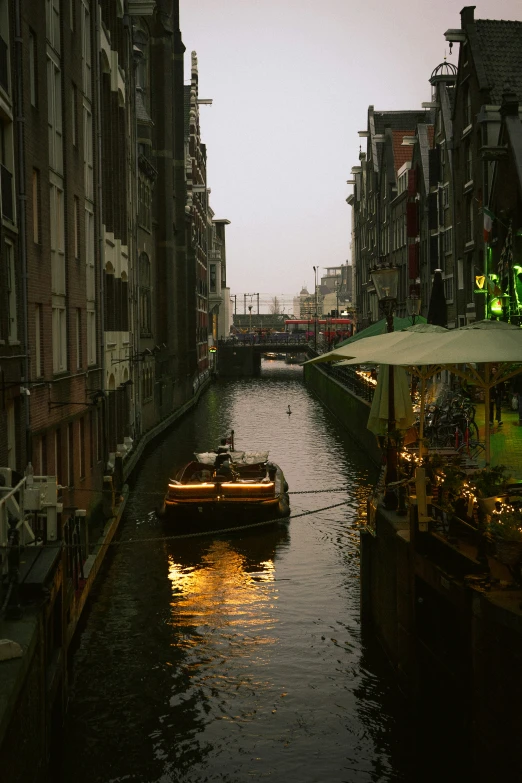 a boat floating down a river next to tall buildings