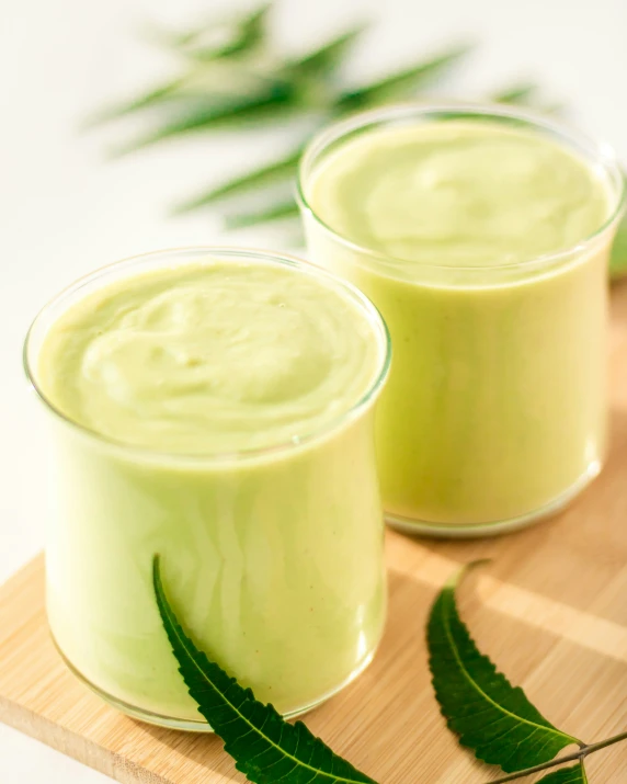 two glasses of smoothie on a small  board