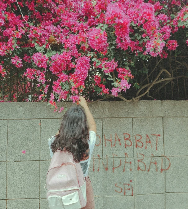 a woman writes words on the wall next to flowers