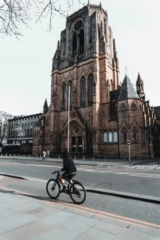 someone riding their bike in front of an old church