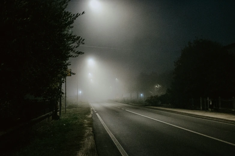 a night view from the side of the road as cars drive by in fog