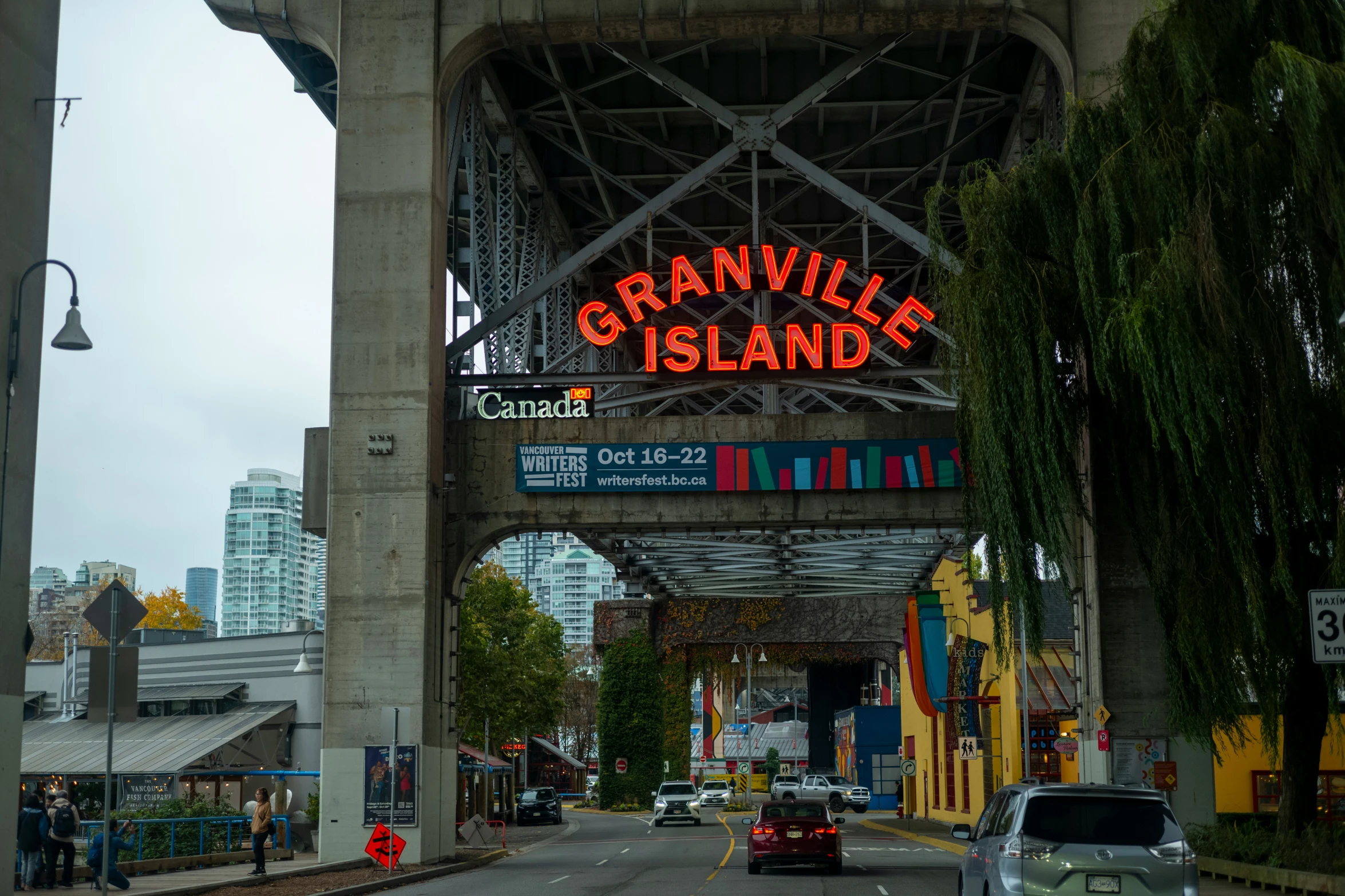 a bridge spanning the width of two roads, is lit up with bright neon signage