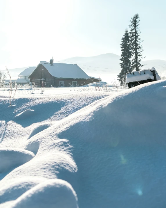 a field is covered in snow and the sky has a barn behind it