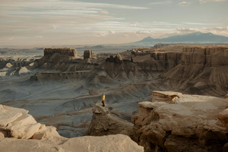 a lone person standing on a rock cliff overlooking the mountains