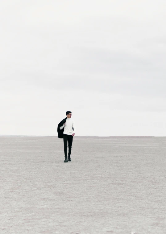 a man in white jacket walking through an open area