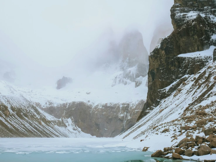 a rocky cliff and a mountain covered in snow